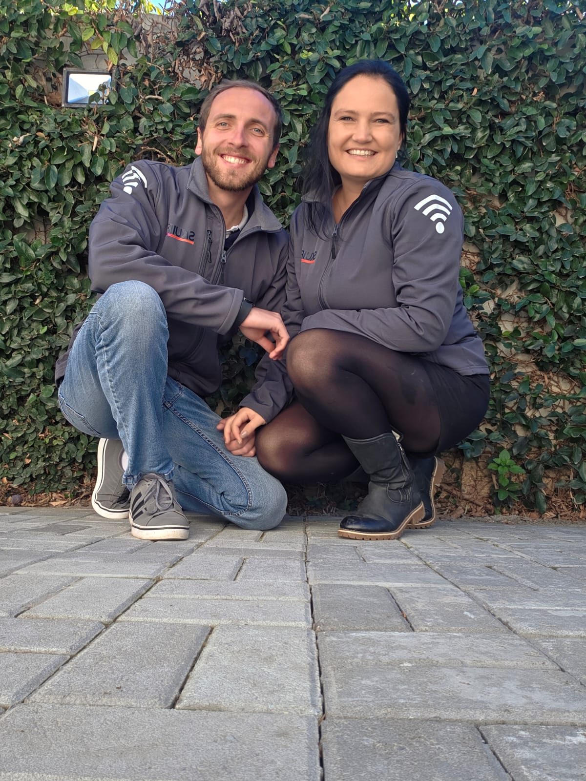 SkuifNet owners Maruschka and Eddie smiling outdoors in branded jackets